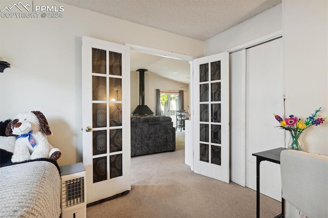 carpeted bedroom featuring lofted ceiling, a textured ceiling, and a wood stove