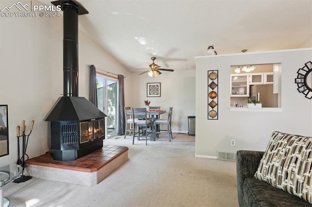 living room featuring ceiling fan, a wood stove, lofted ceiling, and carpet floors