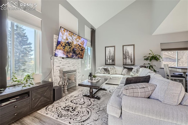 living room with light hardwood / wood-style flooring, a fireplace, high vaulted ceiling, and plenty of natural light