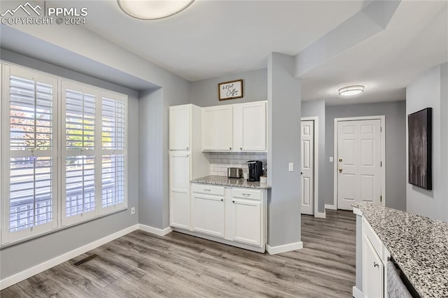 kitchen with white cabinets, light stone counters, and light hardwood / wood-style flooring