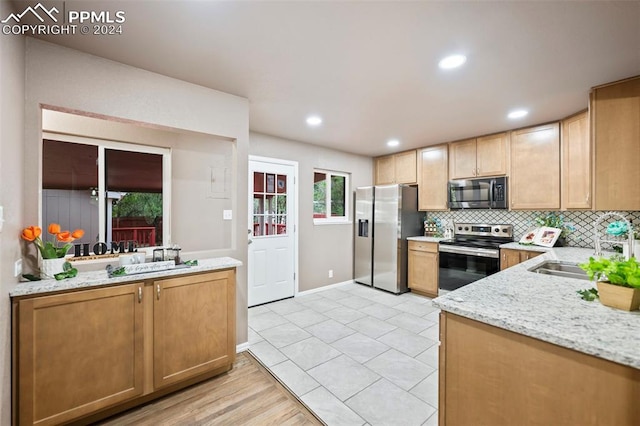 kitchen featuring decorative backsplash, light hardwood / wood-style flooring, sink, appliances with stainless steel finishes, and light stone counters