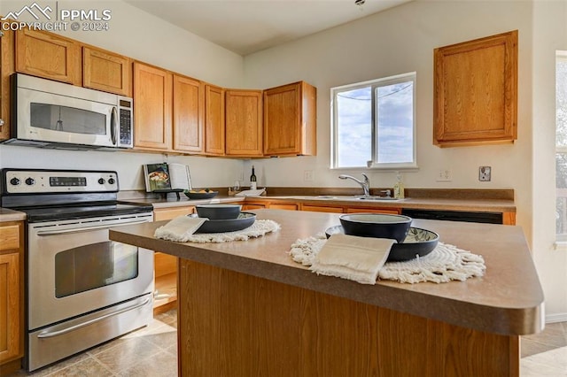 kitchen with light tile patterned flooring, stainless steel appliances, a kitchen island, and sink