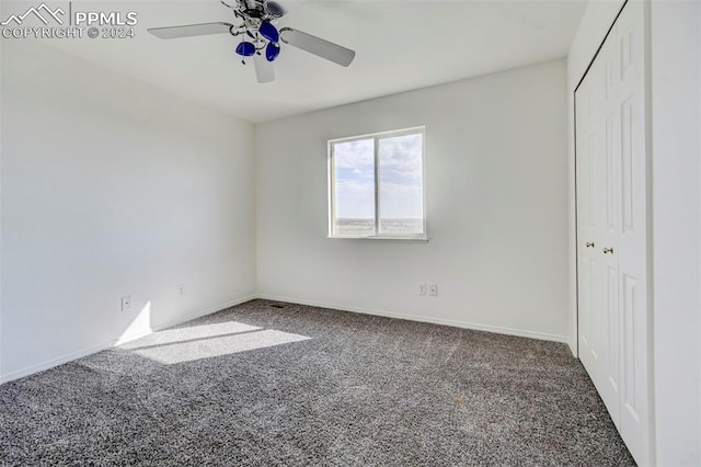 unfurnished bedroom featuring a closet, dark carpet, and ceiling fan