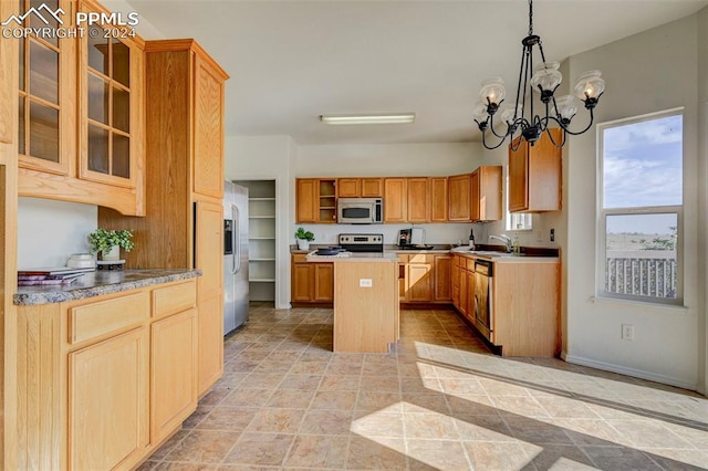 kitchen with appliances with stainless steel finishes, sink, a notable chandelier, a kitchen island, and hanging light fixtures