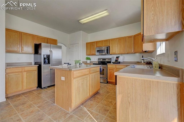 kitchen featuring light brown cabinets, stainless steel appliances, a kitchen island, and sink