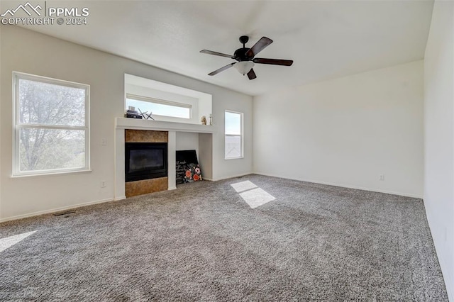 unfurnished living room featuring ceiling fan, a fireplace, and carpet