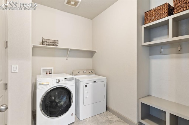 clothes washing area with light tile patterned flooring and washing machine and dryer