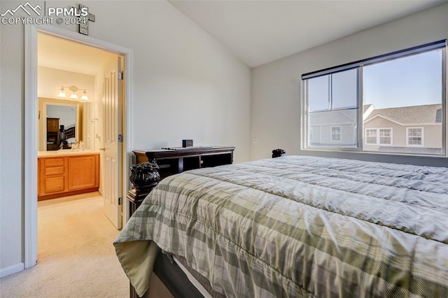 carpeted bedroom with ensuite bathroom and vaulted ceiling