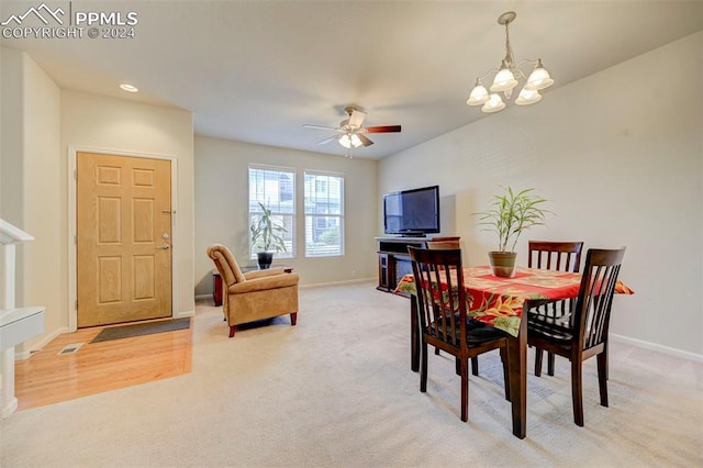 carpeted dining space with ceiling fan with notable chandelier