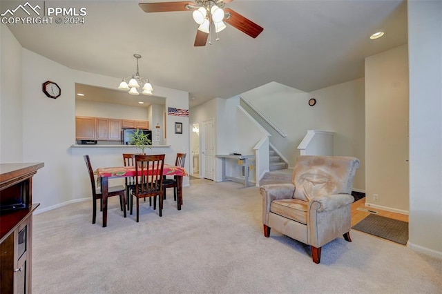 dining space featuring light carpet and ceiling fan with notable chandelier