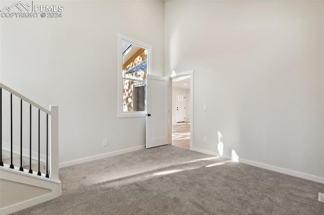 unfurnished room with carpet flooring and a towering ceiling