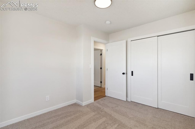 unfurnished bedroom featuring light colored carpet and a closet