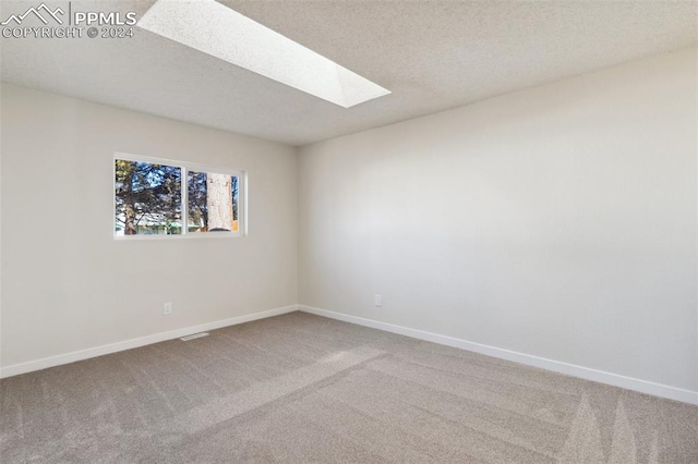 unfurnished room with carpet flooring, a skylight, and a textured ceiling