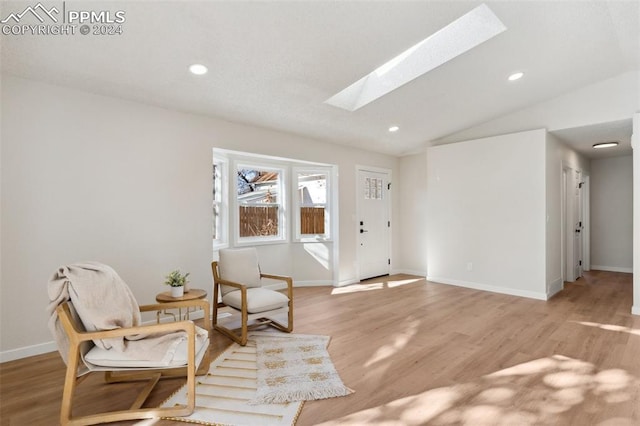 sitting room with light wood-type flooring and lofted ceiling with skylight