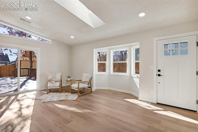 entryway featuring light hardwood / wood-style floors, plenty of natural light, and vaulted ceiling with skylight