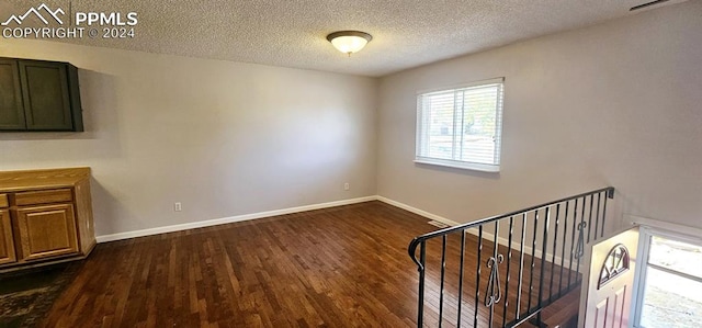 unfurnished room with dark hardwood / wood-style flooring and a textured ceiling