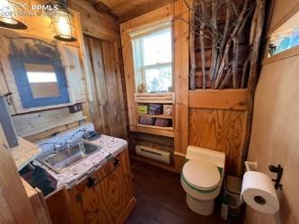 bathroom featuring hardwood / wood-style floors, sink, toilet, and wooden walls