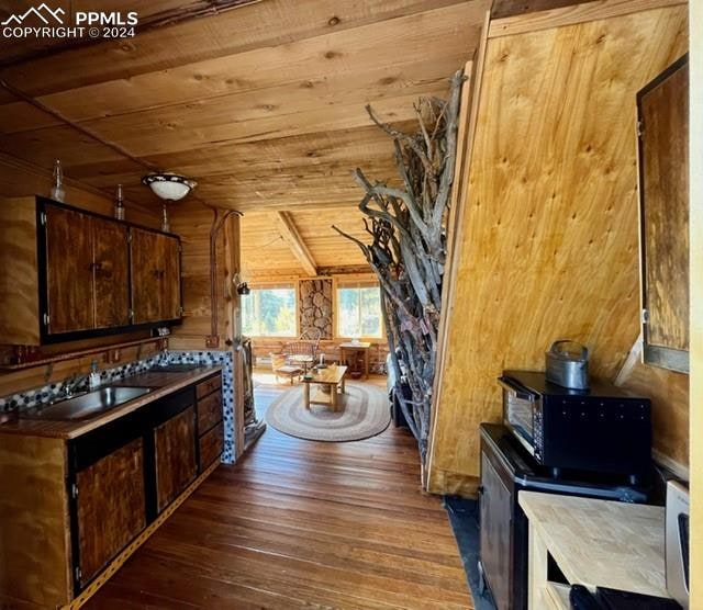 kitchen with sink, vaulted ceiling, dark brown cabinetry, and dark hardwood / wood-style floors