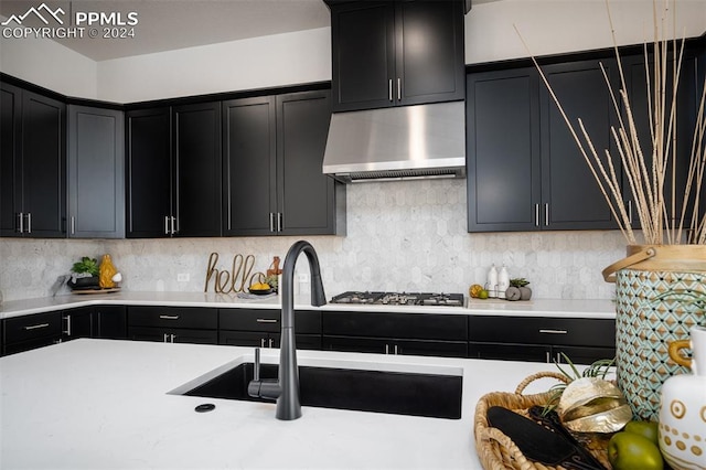 kitchen with sink, decorative backsplash, stainless steel gas stovetop, and extractor fan