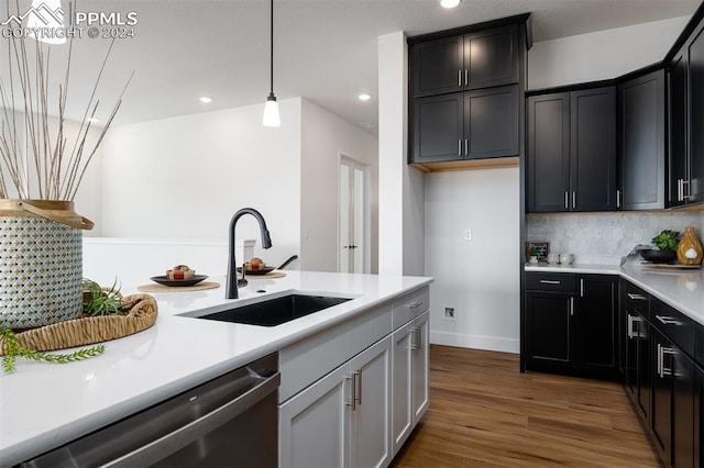 kitchen with dark hardwood / wood-style floors, hanging light fixtures, sink, stainless steel dishwasher, and tasteful backsplash