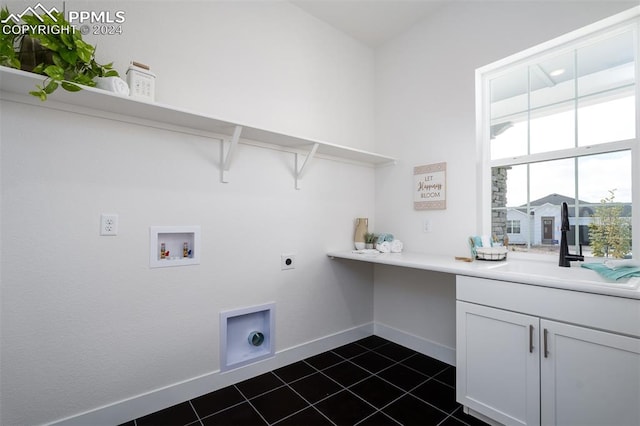 clothes washing area with dark tile patterned floors, electric dryer hookup, hookup for a washing machine, sink, and cabinets