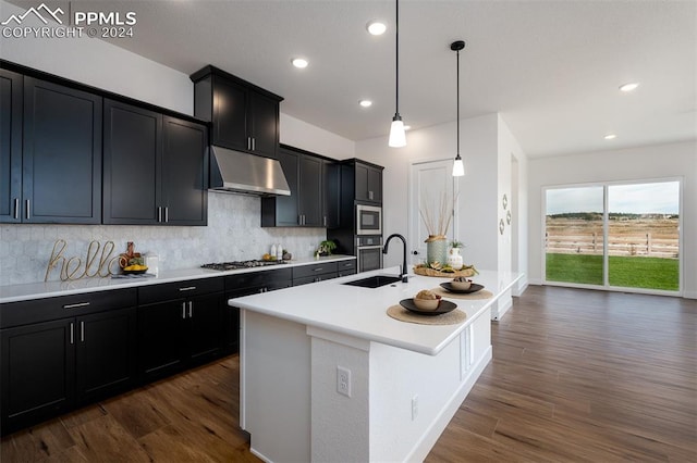 kitchen featuring hanging light fixtures, stainless steel appliances, a center island with sink, sink, and dark hardwood / wood-style flooring