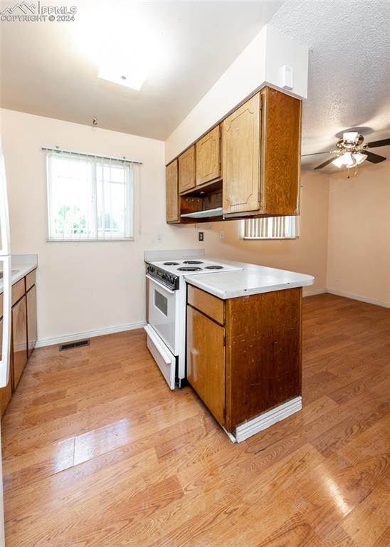 kitchen with ceiling fan, white electric range oven, light hardwood / wood-style flooring, and kitchen peninsula