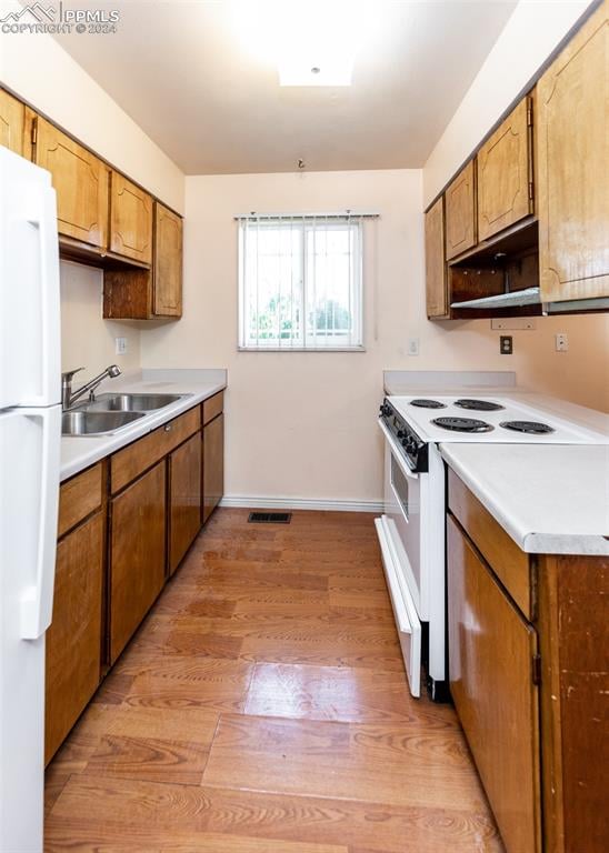 kitchen with light hardwood / wood-style floors, sink, and white appliances