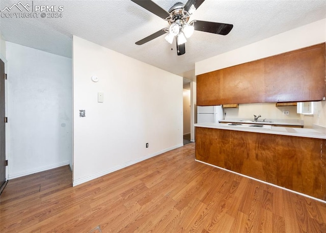 kitchen with light hardwood / wood-style floors, a textured ceiling, and white refrigerator