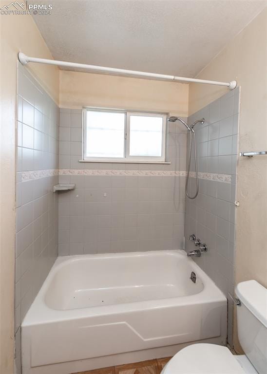 bathroom with toilet and tiled shower / bath combo