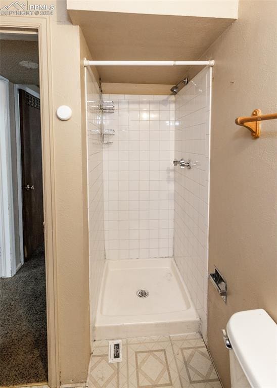 bathroom featuring toilet and a tile shower