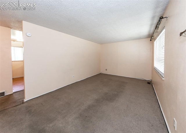 carpeted empty room featuring a textured ceiling