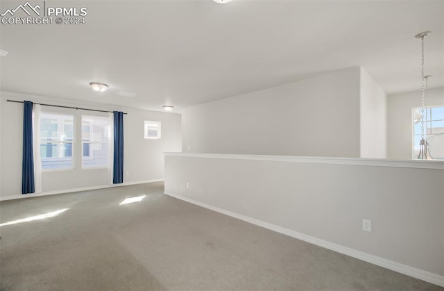 unfurnished room featuring carpet and a notable chandelier