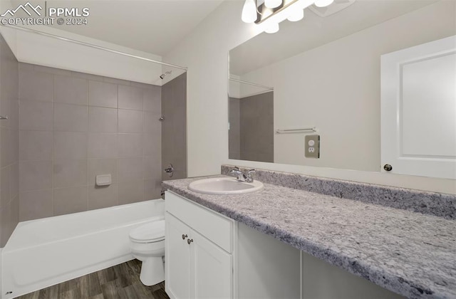 full bathroom featuring tiled shower / bath, vanity, wood-type flooring, and toilet