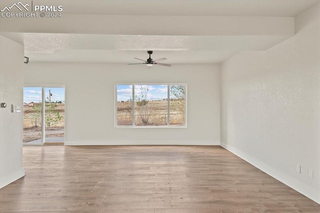 spare room with beamed ceiling, hardwood / wood-style floors, ceiling fan, and plenty of natural light