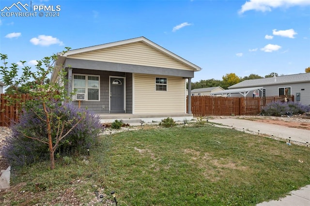 bungalow-style home with cooling unit and a front lawn