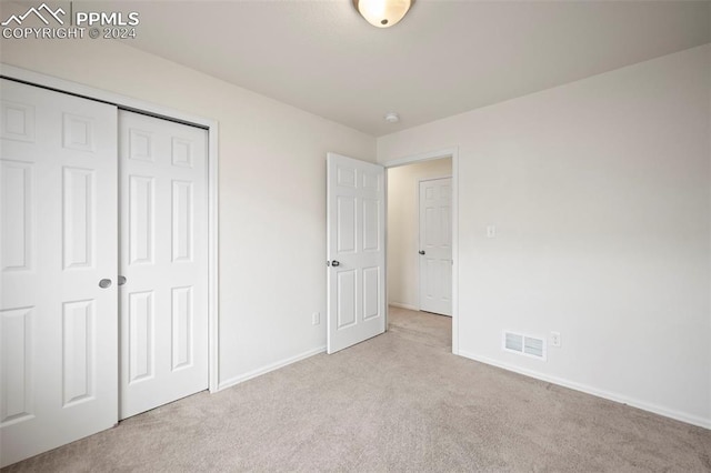 unfurnished bedroom with light carpet and a closet