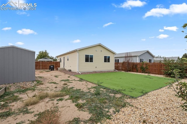 back of house featuring a shed and a lawn