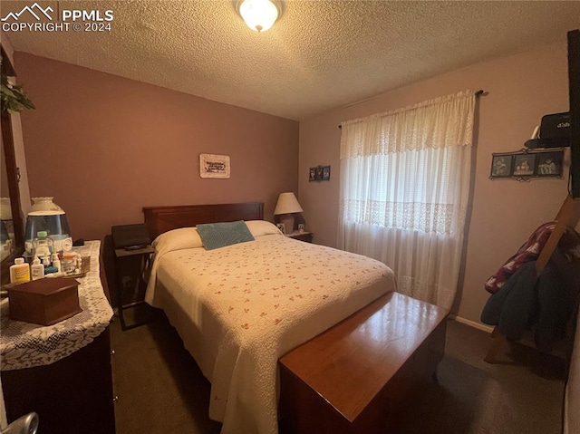 bedroom featuring dark carpet and a textured ceiling