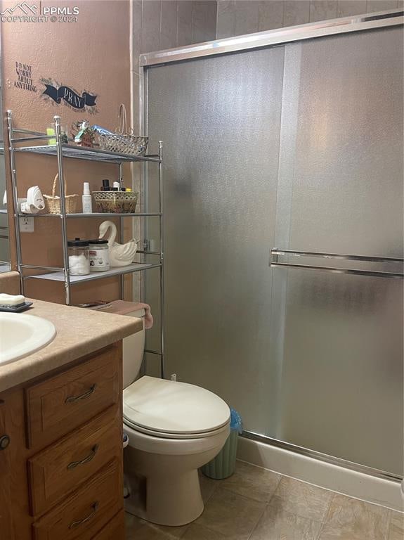 bathroom featuring vanity, tile patterned floors, toilet, and an enclosed shower