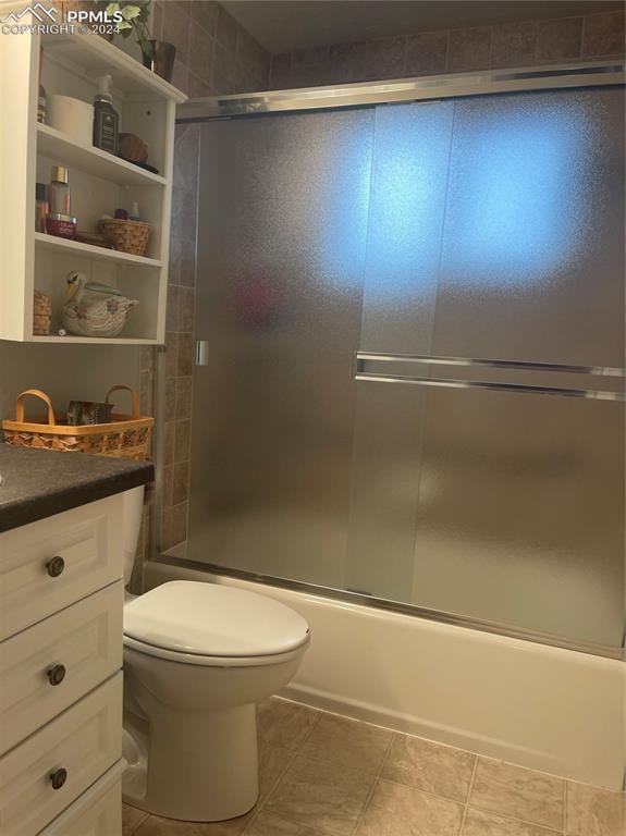 full bathroom featuring toilet, bath / shower combo with glass door, vanity, and tile patterned floors