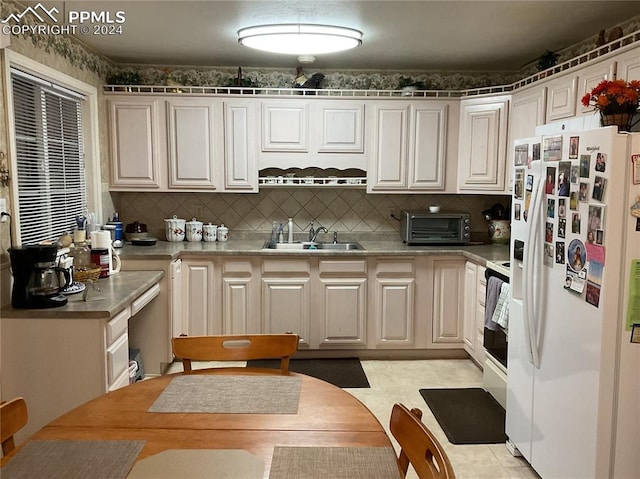 kitchen featuring range, white fridge with ice dispenser, tasteful backsplash, and sink