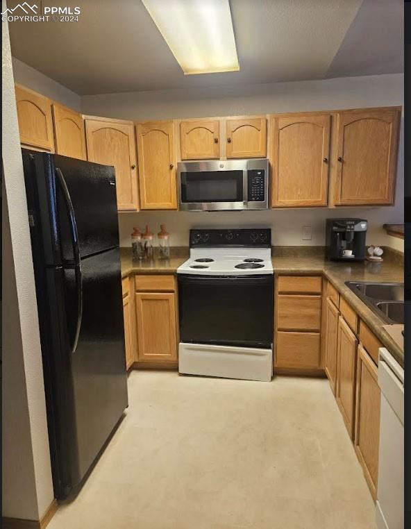 kitchen featuring light brown cabinetry, sink, and white appliances