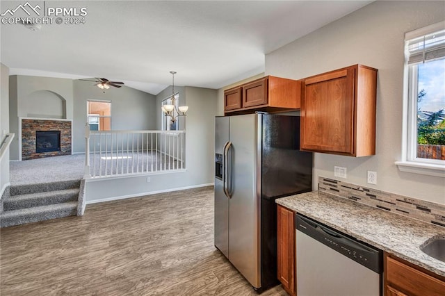 kitchen with decorative backsplash, appliances with stainless steel finishes, light hardwood / wood-style flooring, ceiling fan with notable chandelier, and light stone counters