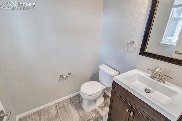 bathroom with vanity, toilet, and hardwood / wood-style floors