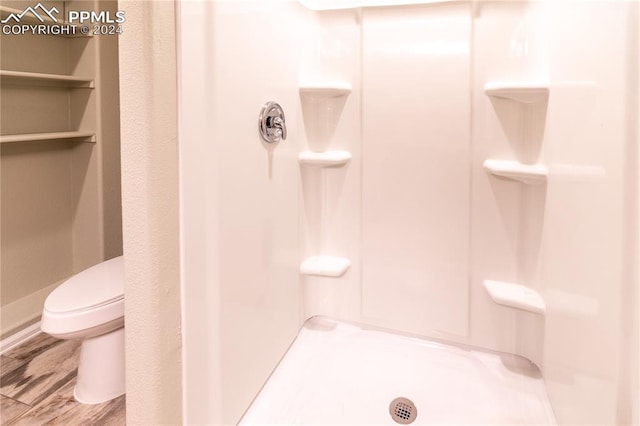 bathroom featuring toilet, a shower, and hardwood / wood-style floors