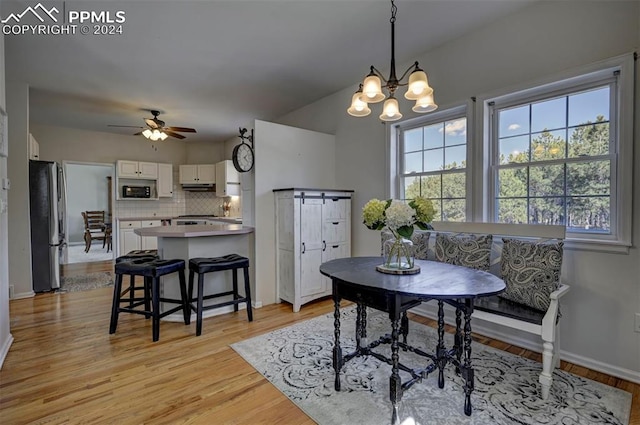 dining area featuring light hardwood / wood-style floors, a barn door, and ceiling fan with notable chandelier