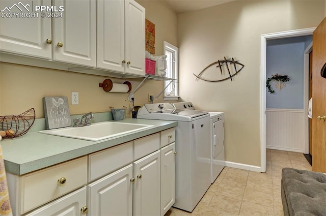 clothes washing area with light tile patterned floors, cabinets, sink, and washer and clothes dryer