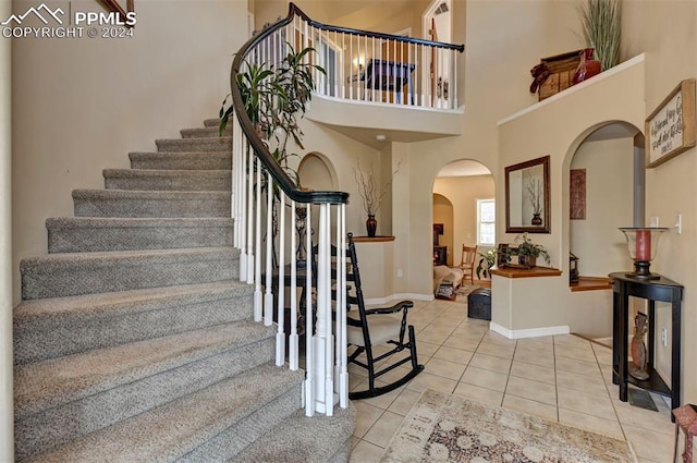 entryway with a towering ceiling and light tile patterned floors