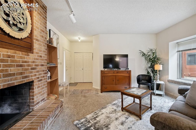 carpeted living room featuring track lighting, a brick fireplace, and a textured ceiling